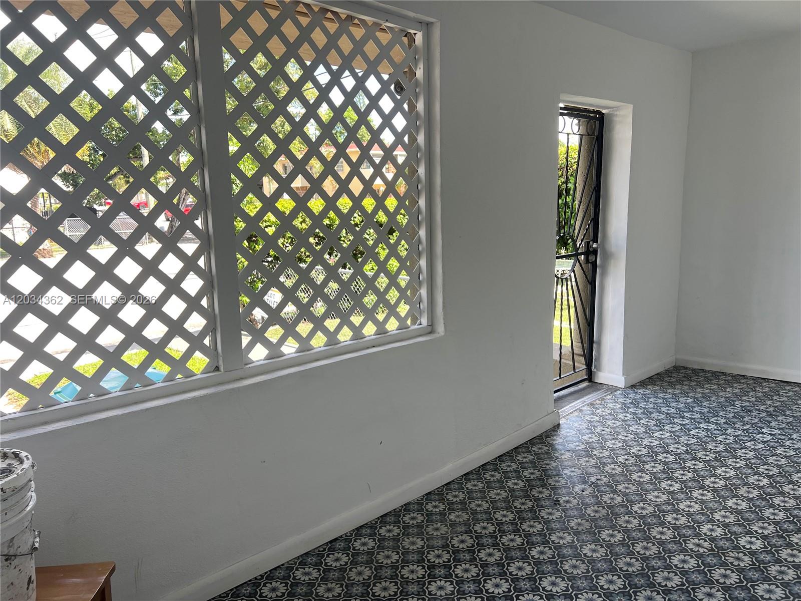 A sunroom features patterned tile flooring, white walls, and a lattice-covered window — 842 SW 12th Ave, Miami FL 33130, MIAMI, FL