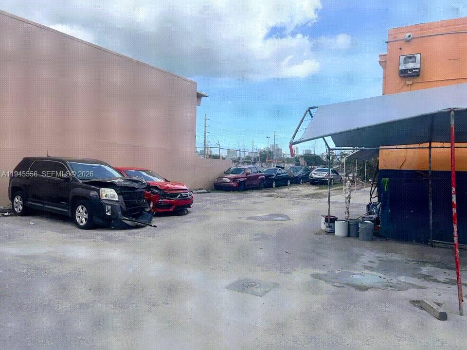 A paved outdoor lot features several damaged vehicles parked beside two commercial buildings — 2005 NW 10th Ave, Miami FL 33127, MIAMI, FL