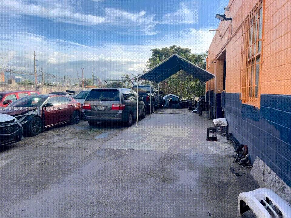 An outdoor parking area features a metal canopy structure next to an orange building — 2005 NW 10th Ave, Miami FL 33127, MIAMI, FL