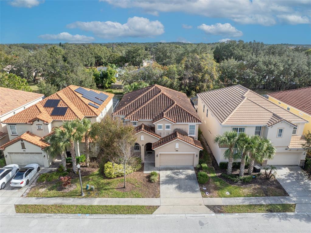 An aerial view shows three suburban houses with tile roofs and driveways on a street — 5244 OAKBOURNE AVENUE, DAVENPORT, FL