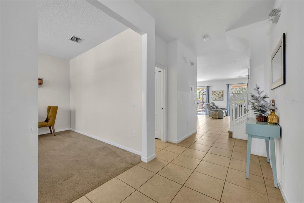 A tiled entryway leads to a carpeted room and a staircase with a small console table — 5244 OAKBOURNE AVENUE, DAVENPORT, FL