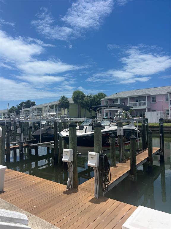A boat is docked at a wooden pier in front of multi-story residential buildings — 00 COQUINA KEY DRIVE SE UNIT 107SS, ST PETERSBURG, FL