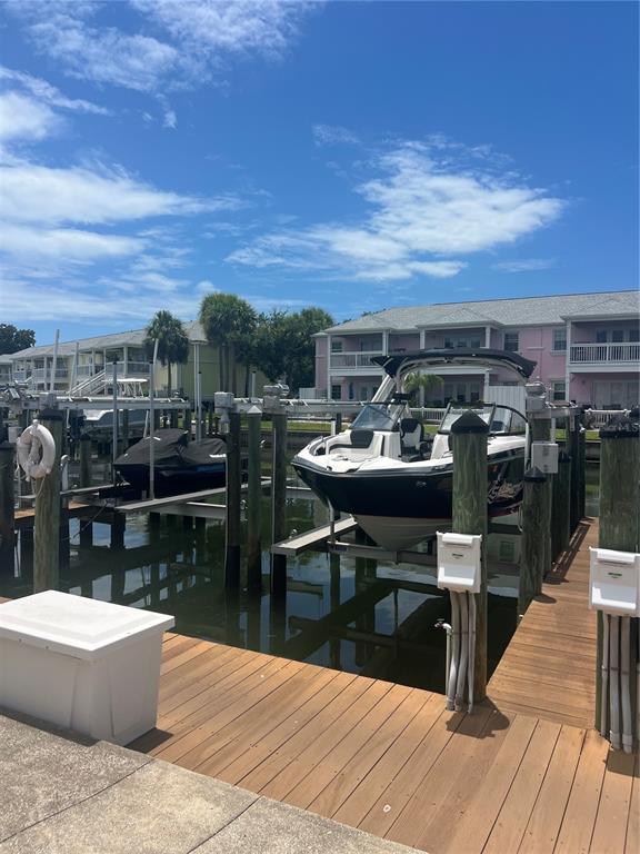 A boat and a jet ski are docked at a wooden pier near residential buildings — 00 COQUINA KEY DRIVE SE UNIT 107SS, ST PETERSBURG, FL