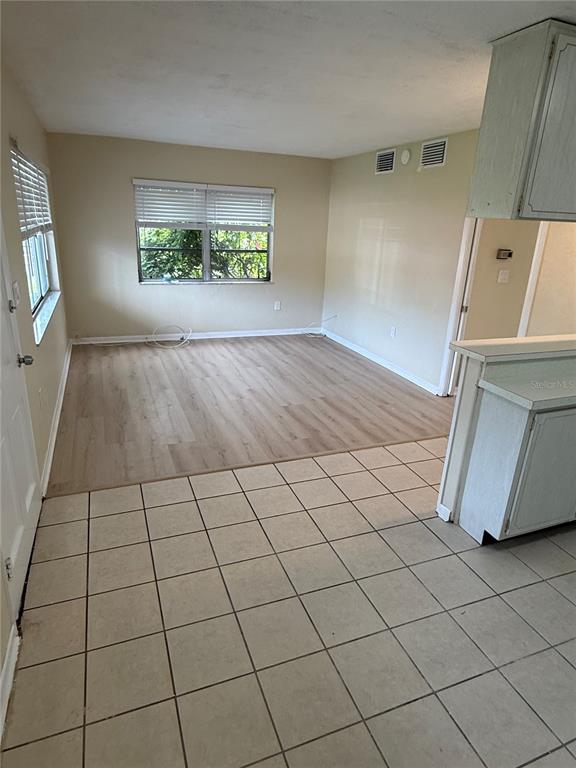 An interior view shows a kitchen with tiled floors transitioning to a wood-floored living area — 2099 KINGS HWY #1 UNIT 1, CLEARWATER, FL