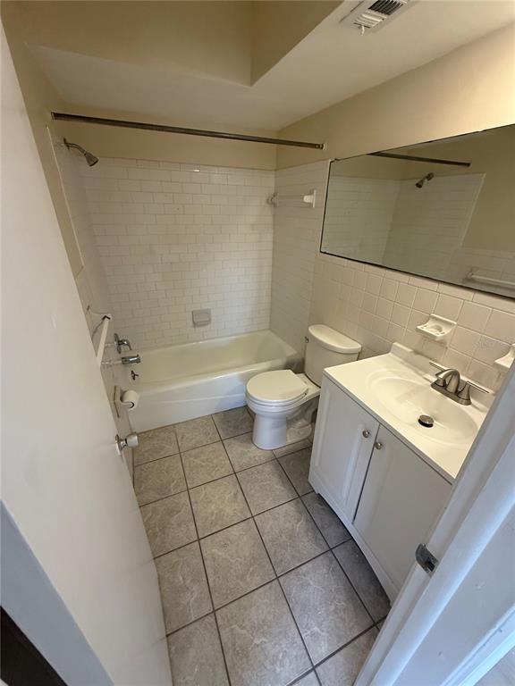 A bathroom features a white vanity, a toilet, and a bathtub with subway tile surround — 2099 KINGS HWY #1 UNIT 1, CLEARWATER, FL