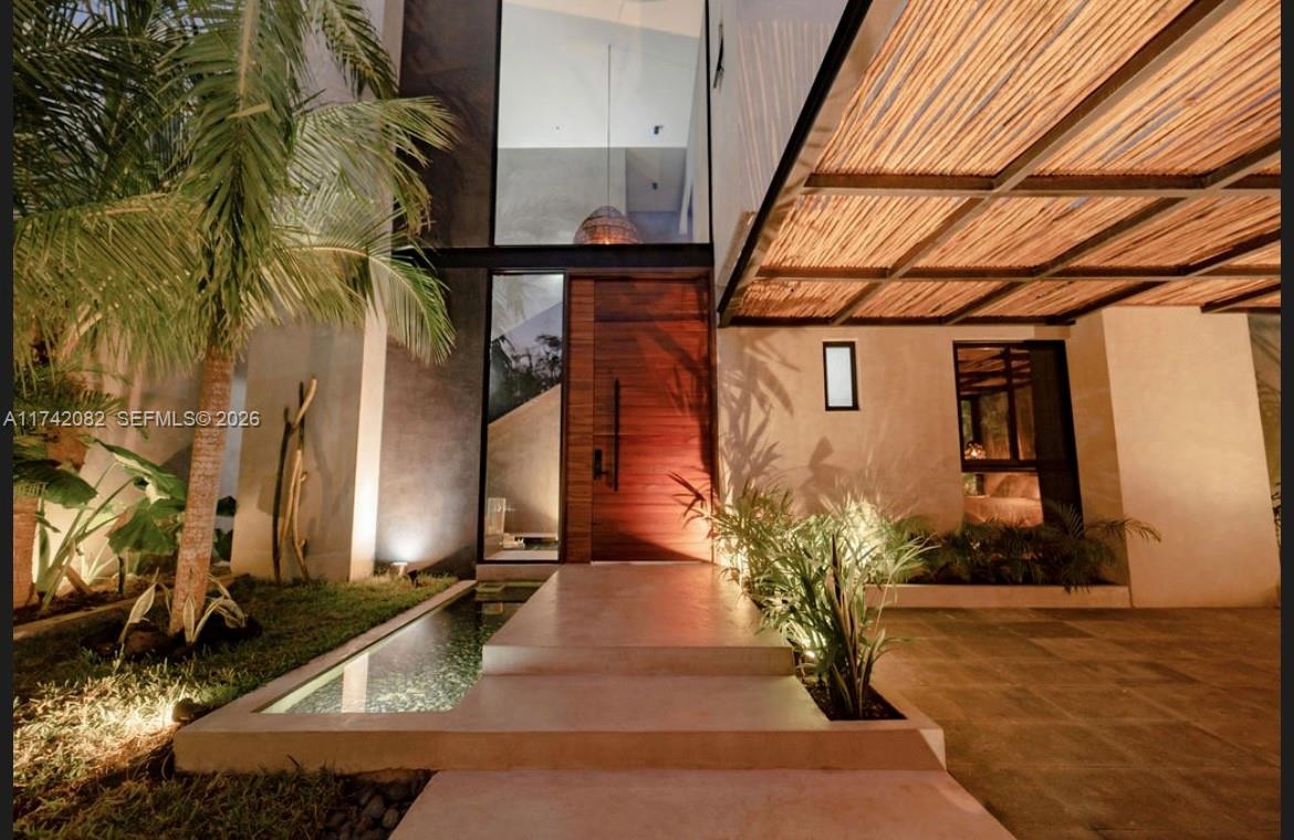 A modern home entrance features a wooden door, a reflecting pool, and a slatted canopy — Tulum region 15 Mnz 327 lotes 007, ., .