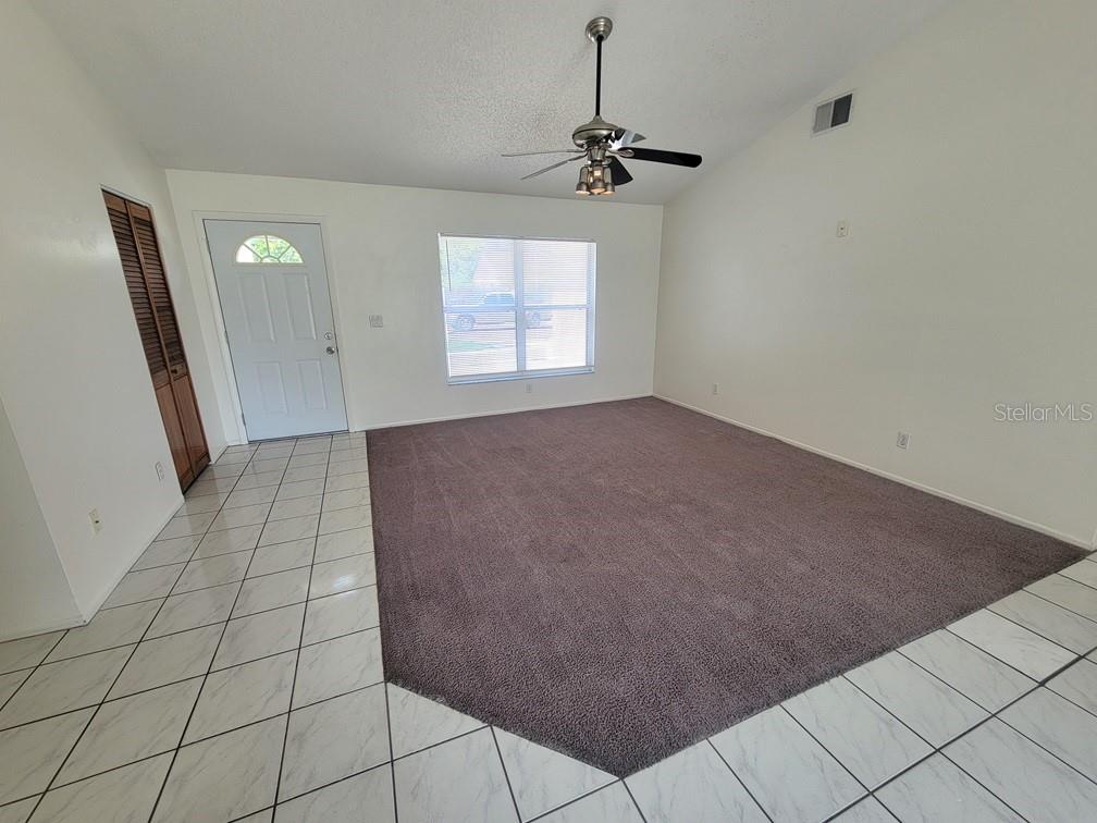 A living room features white walls, a ceiling fan, carpeted flooring, and a tiled entryway — 8224 AUTUMN OAK AVENUE, PORT RICHEY, FL