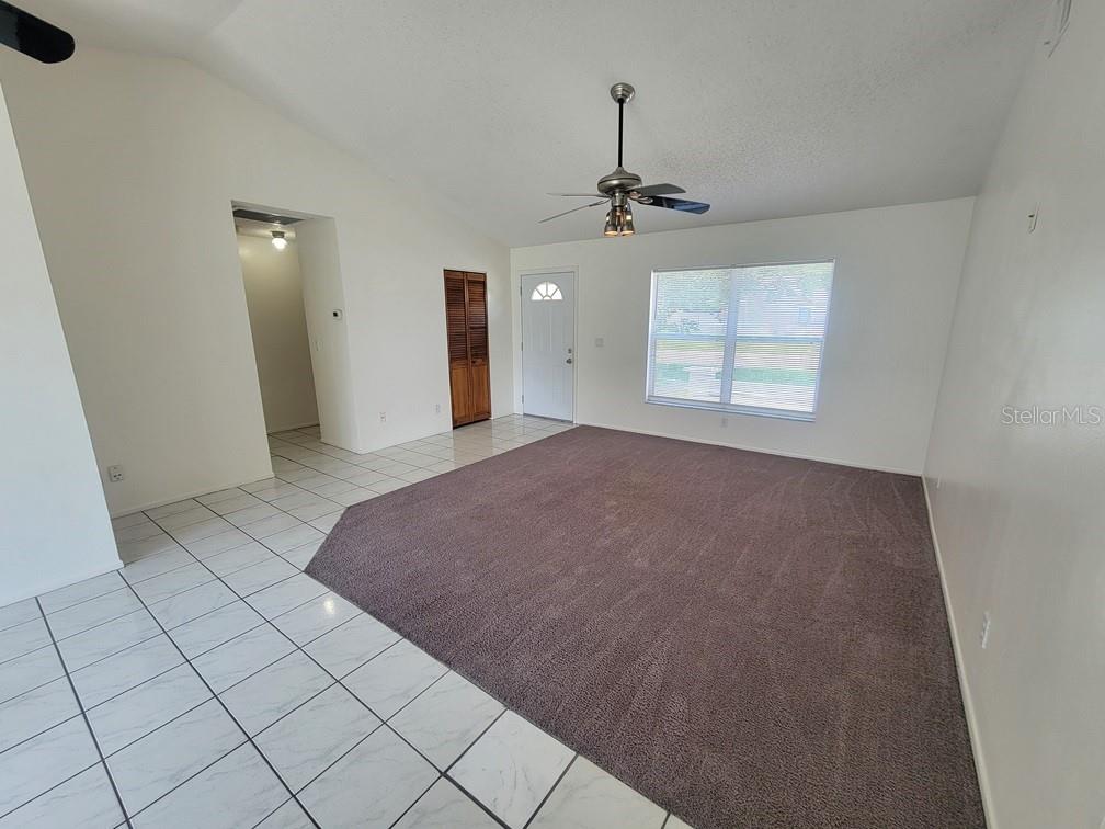 A living room features white walls, a vaulted ceiling, tile flooring, and a carpeted area — 8224 AUTUMN OAK AVENUE, PORT RICHEY, FL