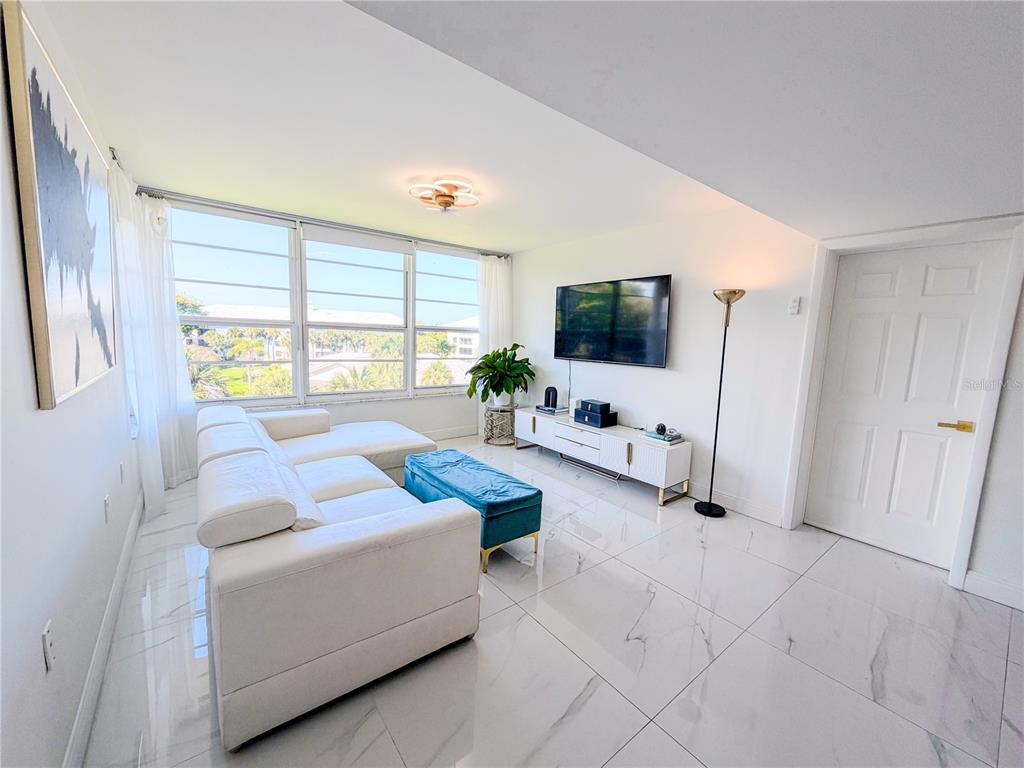 A living room features white tile floors, a white sectional sofa, and a wall-mounted television — 3635 WHITEHALL DRIVE UNIT 401, WEST PALM BEACH, FL