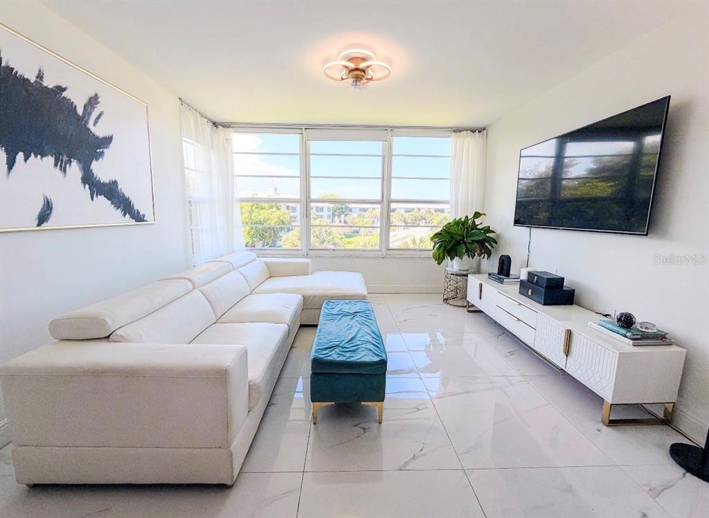 A living room features a white sectional sofa, a blue ottoman, and a wall-mounted television — 3635 WHITEHALL DRIVE UNIT 401, WEST PALM BEACH, FL