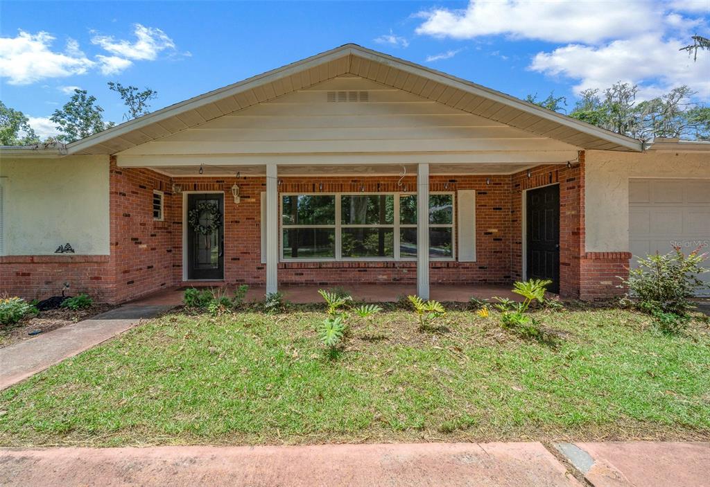 A single-story brick house with a covered front porch and a white gable roof — 1870 SE 38TH STREET, OCALA, FL
