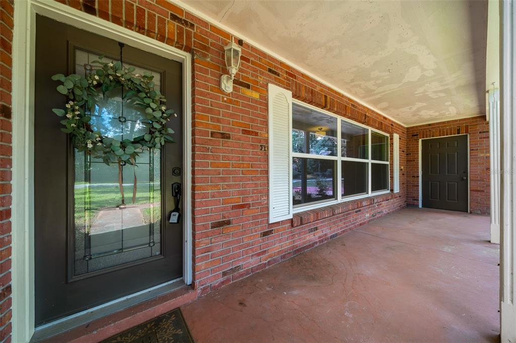 A brick-walled front porch features a dark glass-paneled front door and a secondary door — 1870 SE 38TH STREET, OCALA, FL
