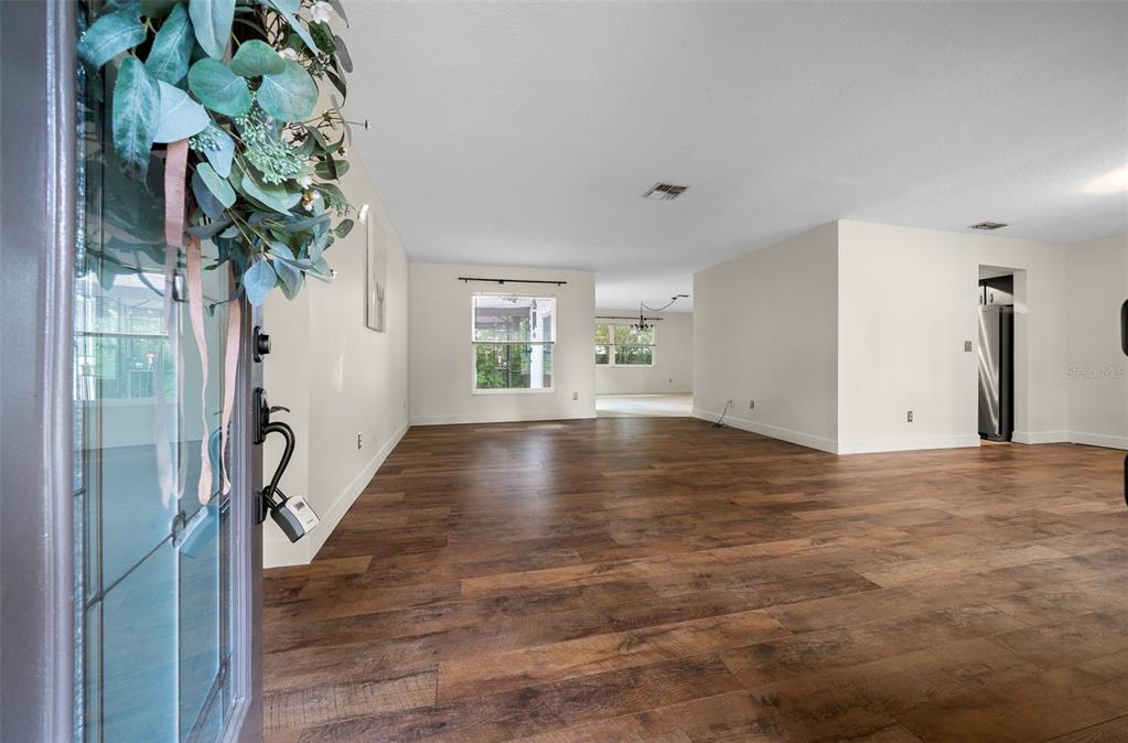 An interior view shows a living area with wood-look flooring and white walls — 1870 SE 38TH STREET, OCALA, FL