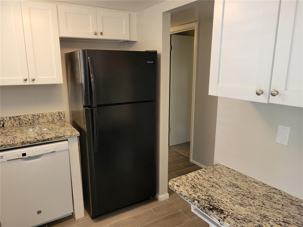 A kitchen features white cabinets, granite countertops, a black refrigerator, and a dishwasher — 2009 CANAL DRIVE UNIT N4, BRADENTON, FL
