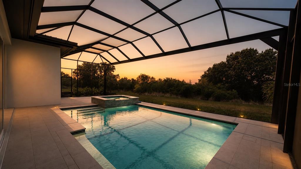 A screened-in patio features a swimming pool with an integrated hot tub at sunset — 269 BLUE PEARL COURT, SARASOTA, FL