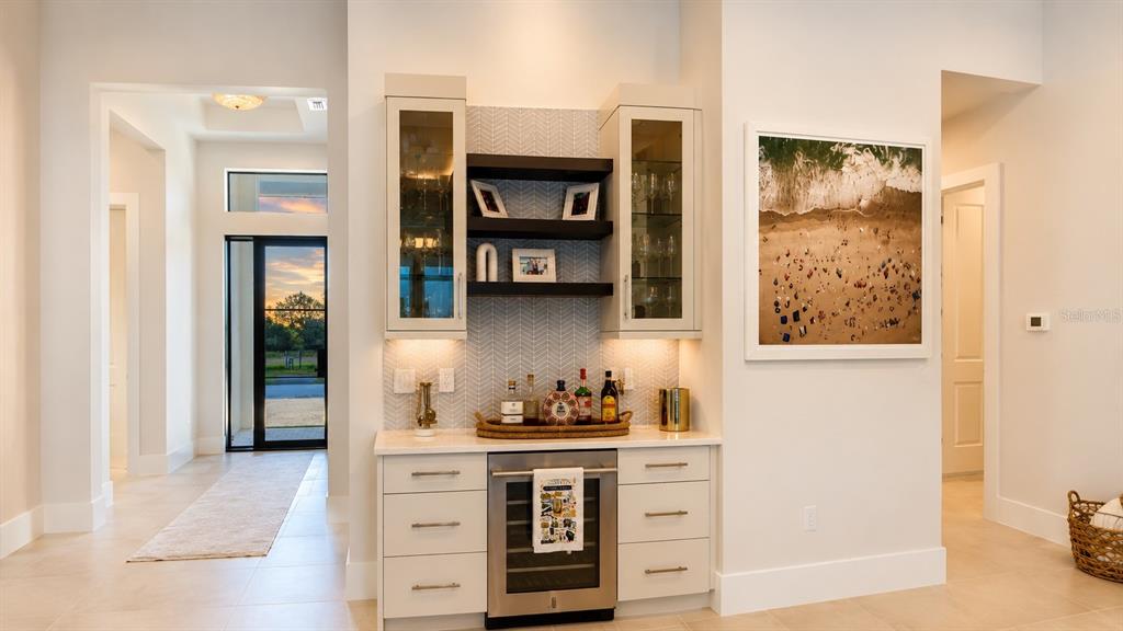 A home bar area features white cabinetry, glass-front upper cabinets, open shelving, and a wine cooler — 269 BLUE PEARL COURT, SARASOTA, FL