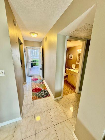 A hallway with tile flooring leads to an exterior door and a bathroom entrance — 2615 Garden Drive S # 101, Lake Worth FL 33461, LAKE WORTH, FL