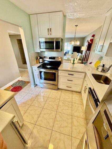 A kitchen with white cabinets, stainless steel appliances, and light-colored tile flooring — 2615 Garden Drive S # 101, Lake Worth FL 33461, LAKE WORTH, FL