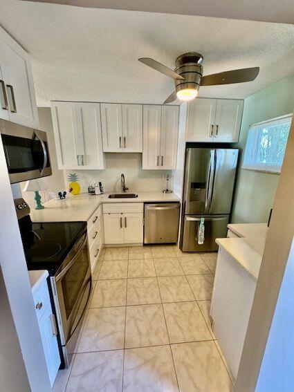 A kitchen features white cabinets, stainless steel appliances, light countertops, and a ceiling fan — 2615 Garden Drive S # 101, Lake Worth FL 33461, LAKE WORTH, FL