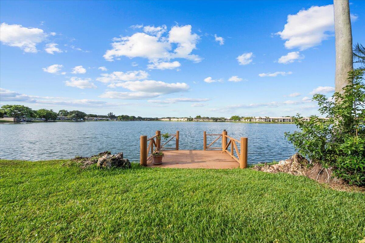 A wooden dock extends into a lake from a grassy lawn under a blue sky — 593 Banks Road # 593, Margate FL 33063, MARGATE, FL