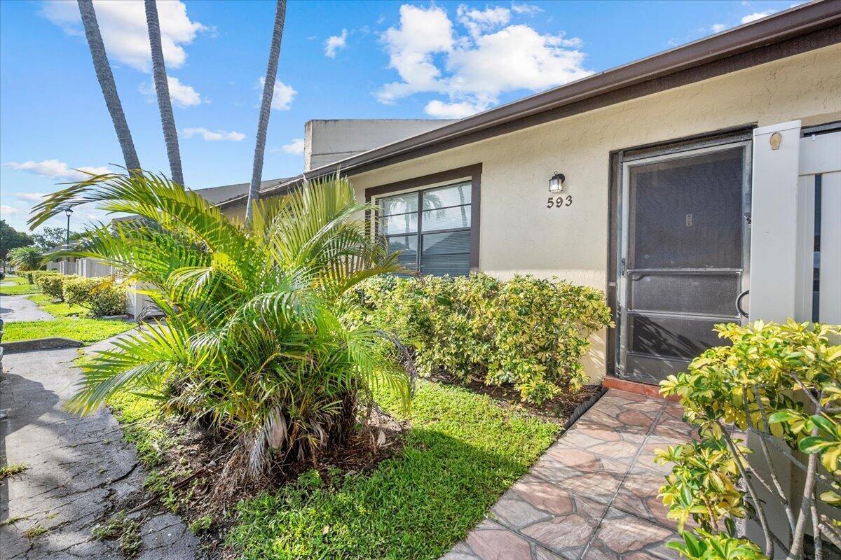 A tan exterior wall with a screen door, house number 593, and a landscaped front yard — 593 Banks Road # 593, Margate FL 33063, MARGATE, FL