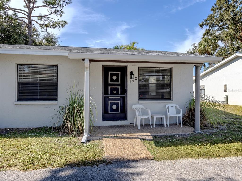 A single-story house exterior features a white facade, a dark front door, and two chairs — 668 SUBSTATION ROAD, VENICE, FL
