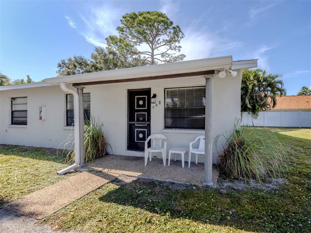 A white single-story house features a covered front porch with two chairs and a door — 668 SUBSTATION ROAD, VENICE, FL