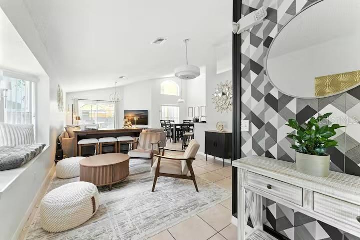 A bright living room features a window seat, patterned wallpaper, and a modern dining area — 1017 LAKE BERKLEY DR, KISSIMMEE, FL