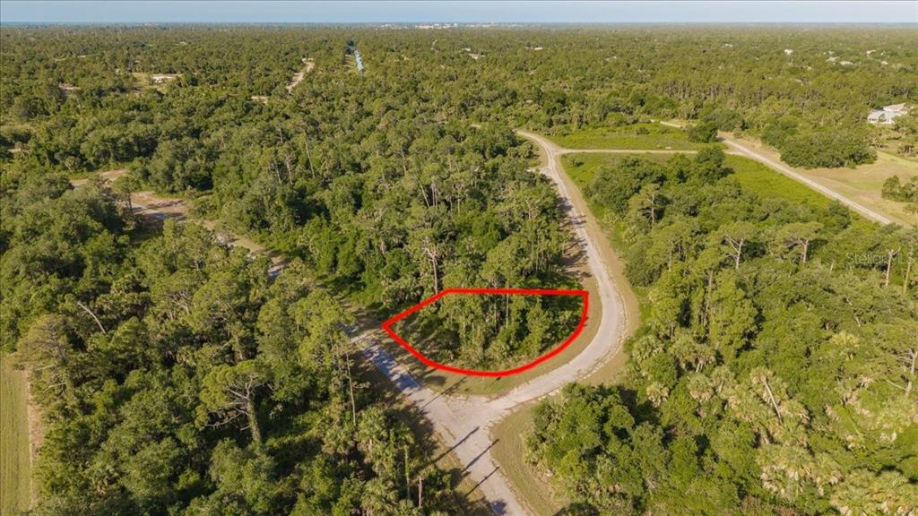 An aerial view shows a wooded, undeveloped lot outlined in red along a paved road — LORING DRIVE, NORTH PORT, FL