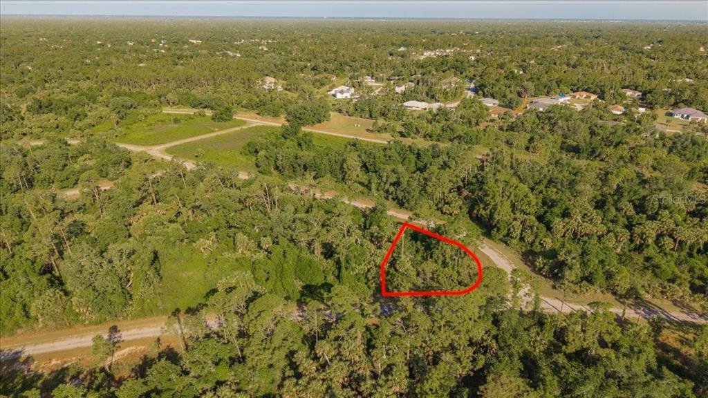 An aerial view shows a wooded, undeveloped lot outlined in red along a dirt road — LORING DRIVE, NORTH PORT, FL