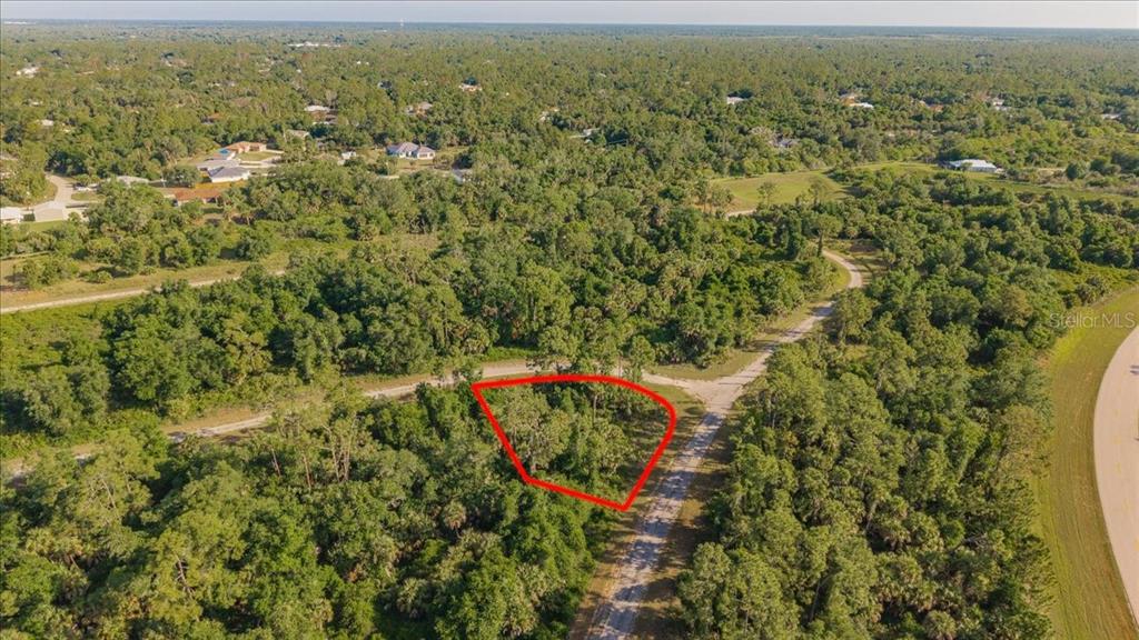 An aerial view shows a wooded, undeveloped lot outlined in red next to a road — LORING DRIVE, NORTH PORT, FL