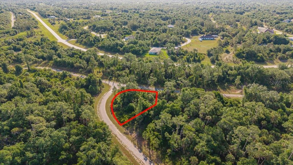 An aerial view shows a vacant, wooded lot outlined in red along a paved road — LORING DRIVE, NORTH PORT, FL