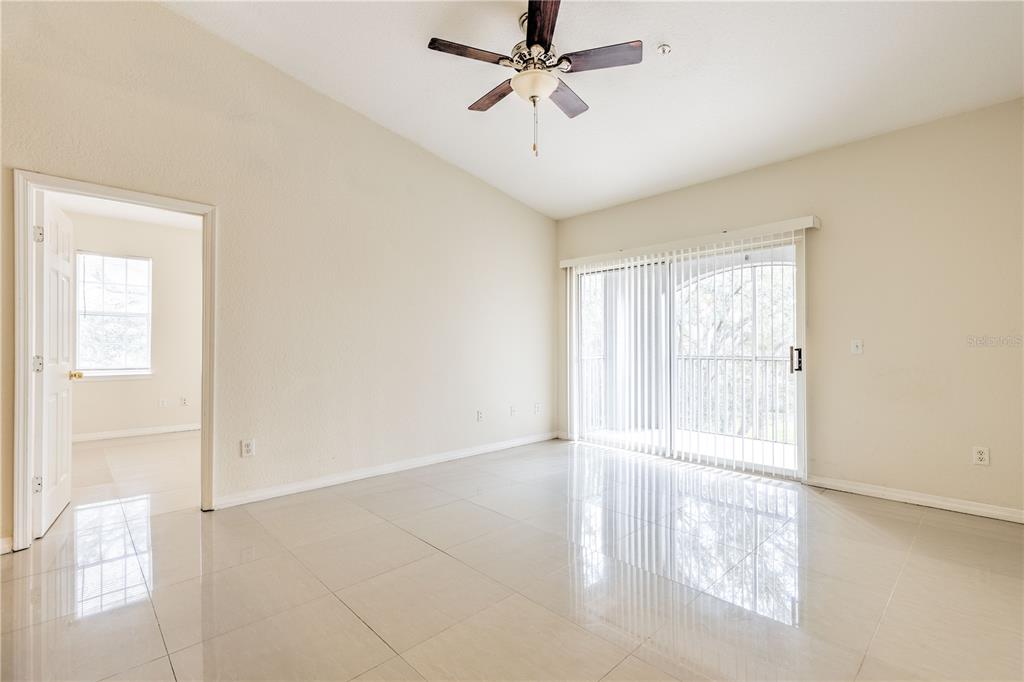 A room with light-colored tile flooring, a ceiling fan, and sliding glass doors to a balcony — 13304 SANCTUARY COVE DRIVE UNIT 303, TAMPA, FL