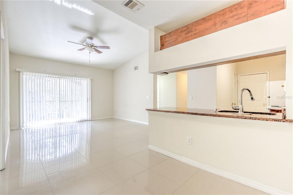 A bright living room with tile floors and a kitchen pass-through with granite countertops — 13304 SANCTUARY COVE DRIVE UNIT 303, TAMPA, FL