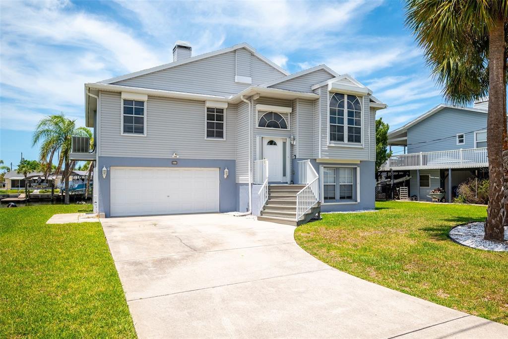 A two-story house with light gray siding, a white garage door, and a front staircase — 4263 TAHITI DRIVE, HERNANDO BEACH, FL