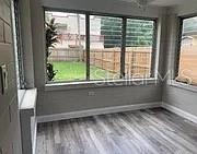 A sunroom with gray wood-look flooring and large windows overlooking a fenced backyard — 981 ARAGON AVENUE, WINTER PARK, FL