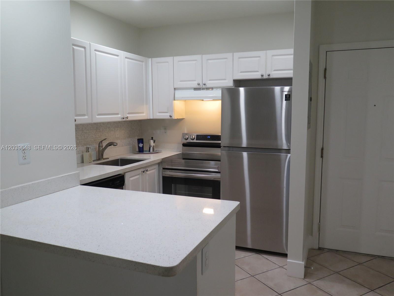 A kitchen features white cabinets, stainless steel appliances, and light-colored quartz countertops — 1918 Brickell Ave # 101, Miami FL 33129, MIAMI, FL