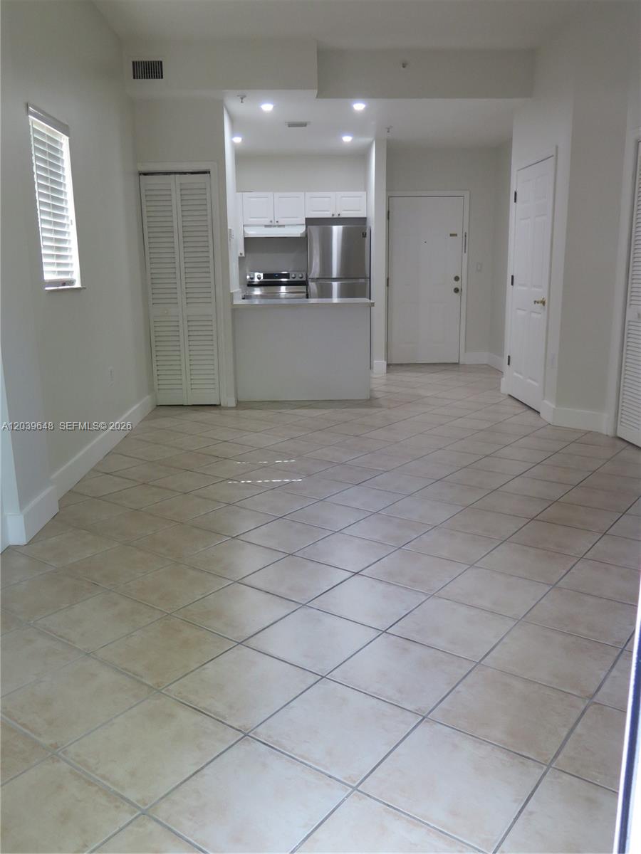 An open-concept living area features light-colored tile flooring and a kitchen with stainless steel appliances — 1918 Brickell Ave # 101, Miami FL 33129, MIAMI, FL