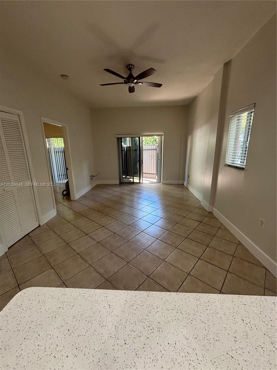 A living room with beige tile flooring, a ceiling fan, and sliding glass patio doors — 1918 Brickell Ave # 101, Miami FL 33129, MIAMI, FL