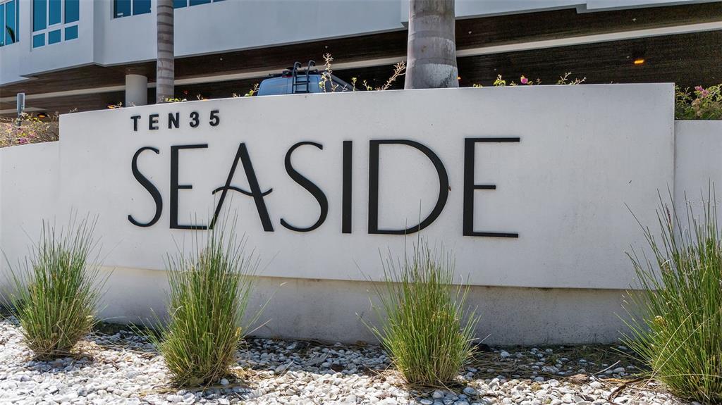 A white sign with the text Ten 35 Seaside stands in front of a modern building — 1035 SEASIDE DRIVE UNIT 308, SARASOTA, FL
