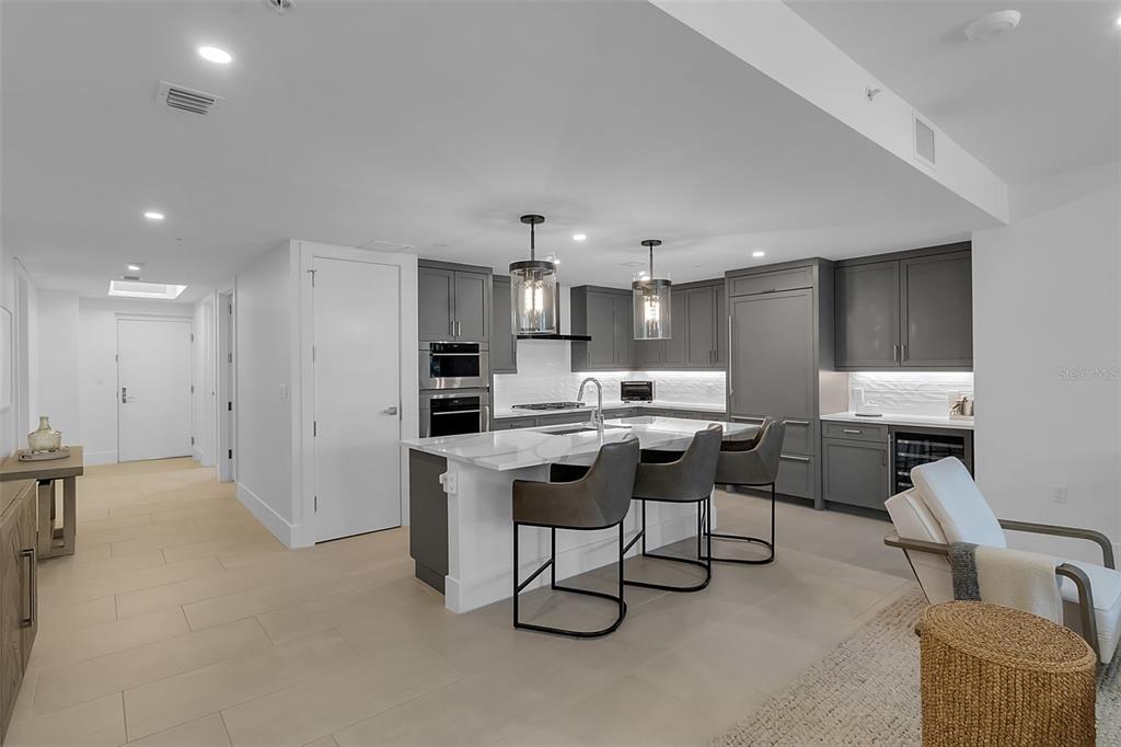 A modern kitchen features gray cabinetry, a white marble island, and three bar stools — 1035 SEASIDE DRIVE UNIT 308, SARASOTA, FL