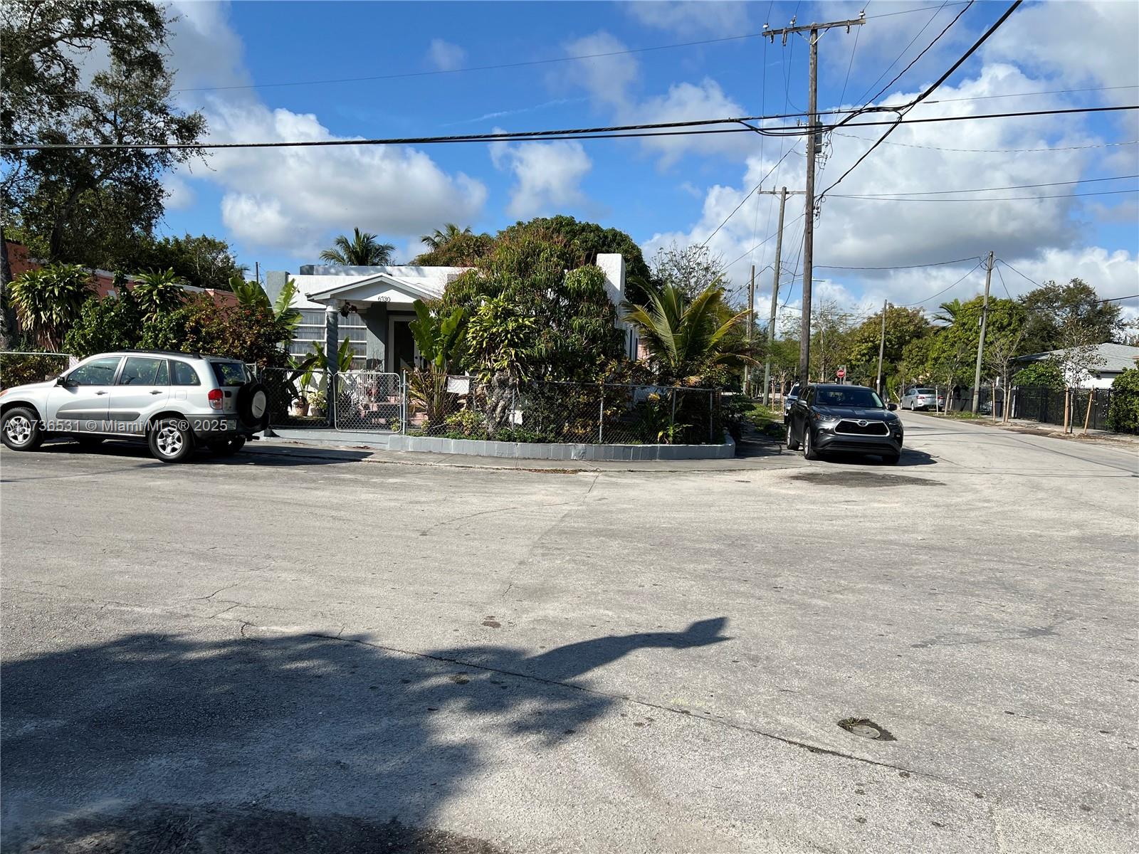 A single-story house with a fenced yard sits on a corner lot with parked cars — 6730 NE MIAMI PL, Miami FL 33138, MIAMI, FL