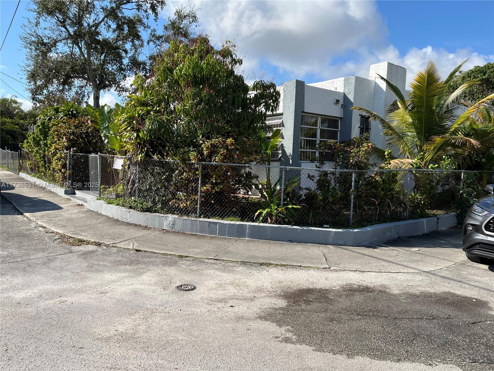 A white single-story house with a chain-link fence and landscaping sits on a corner lot — 6730 NE MIAMI PL, Miami FL 33138, MIAMI, FL