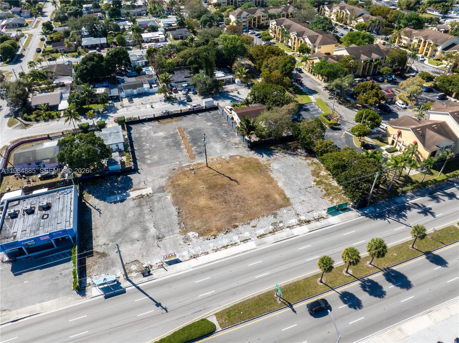 An aerial view shows a vacant, paved rectangular lot situated next to a commercial building — 1410 NW 119th St, Miami FL 33167, MIAMI, FL
