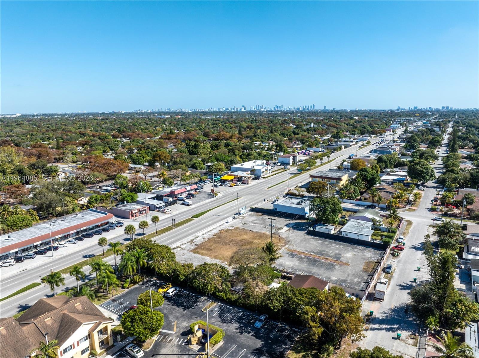 An aerial view shows a commercial street with a vacant lot and surrounding suburban buildings — 1410 NW 119th St, Miami FL 33167, MIAMI, FL