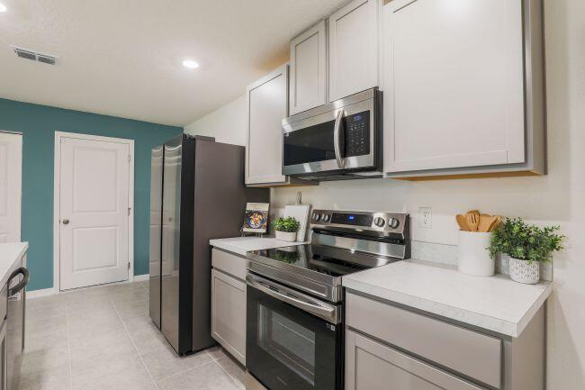 A kitchen features light gray cabinets, stainless steel appliances, and a teal accent wall — 462 Hazel Street, Sebastian FL 32958, SEBASTIAN, FL
