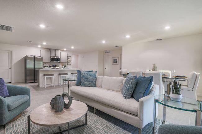 An open-concept living room and kitchen with a sofa, dining table, and stainless steel appliances — 462 Hazel Street, Sebastian FL 32958, SEBASTIAN, FL