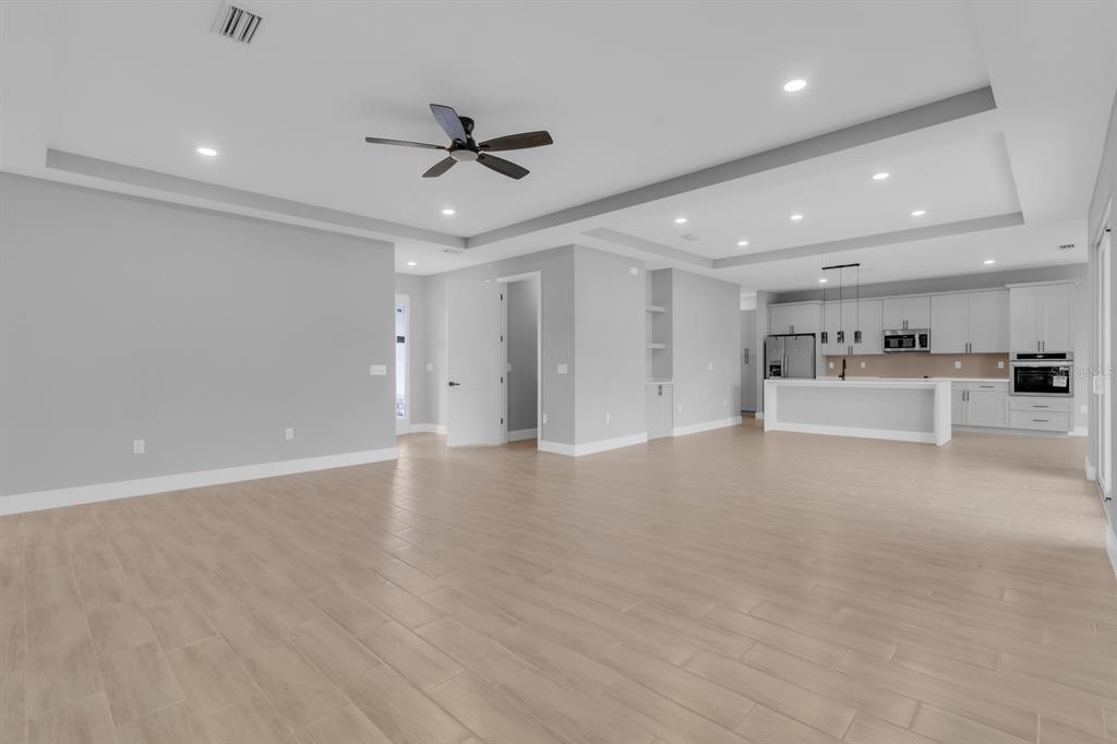 An open-concept living room and kitchen with light wood-look tile flooring and recessed lighting — 1821 MISSOURI ROAD NW, PALM BAY, FL
