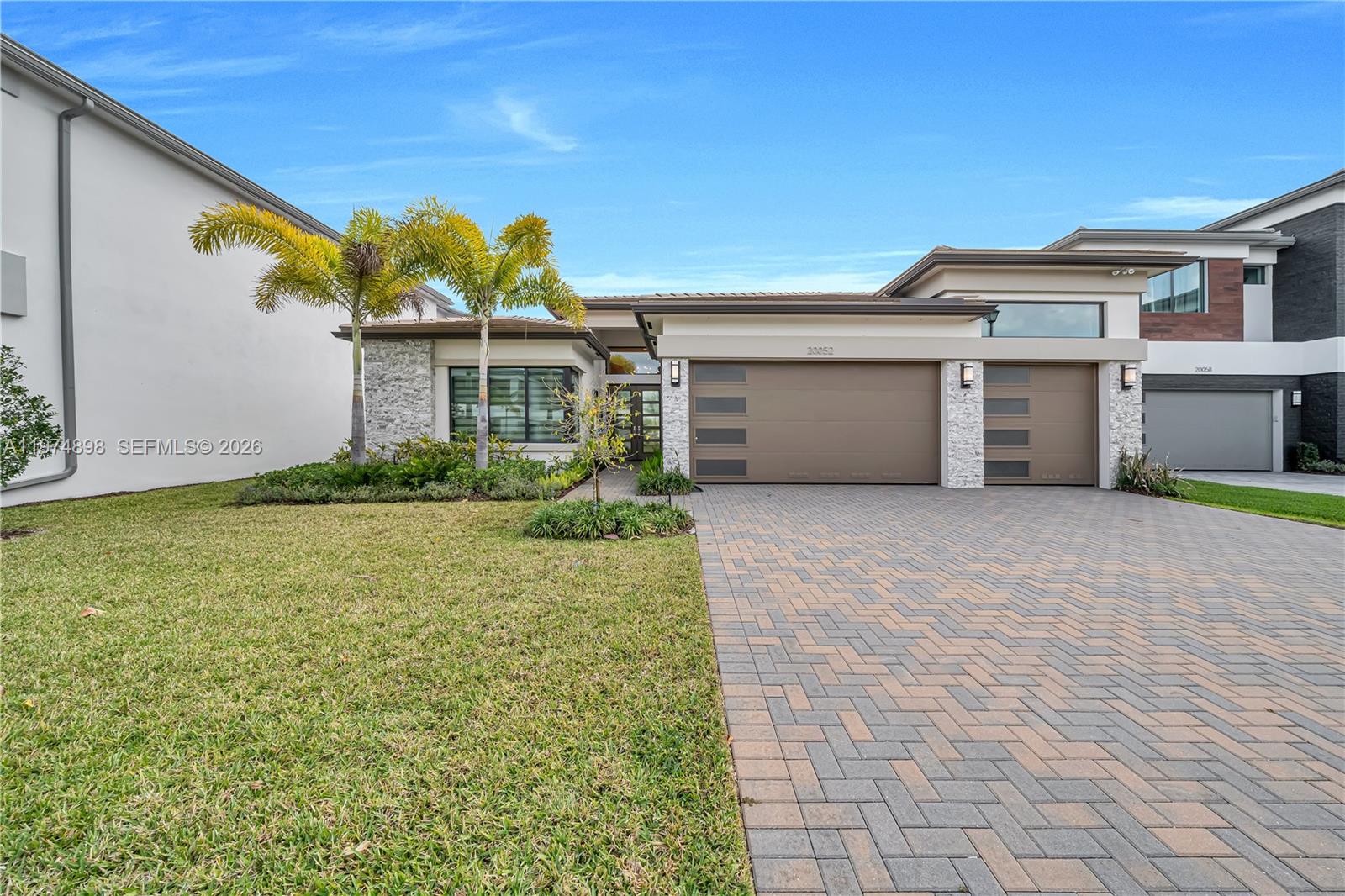 A modern open-concept living room and kitchen featuring white cabinetry, marble floors, and large windows — 20052 Pacific Dunes Dr, Boca Raton FL 33434, BOCA RATON, FL