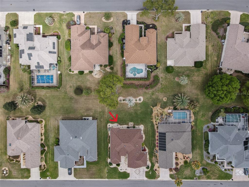 This aerial view shows a residential neighborhood with several houses, swimming pools, and lawns — 9435 SE 124TH PLACE, SUMMERFIELD, FL